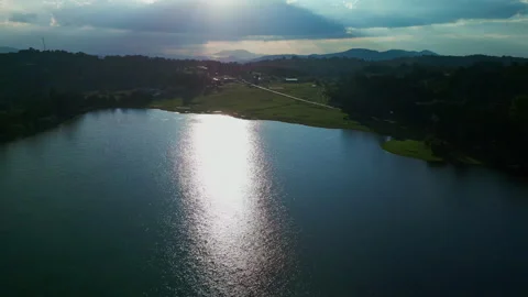 Sun reflection streak across a reservoir with silhouetted hills brightening Stock Footage 346014952