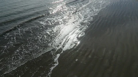 The sun reflects off  of small waves breaking on an empty beach. Stock Footage 119178662