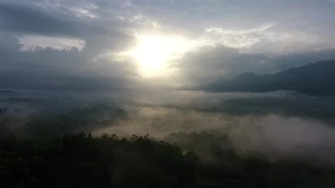 The sun rises and is covered by clouds over the mountain Stock Footage 213922636