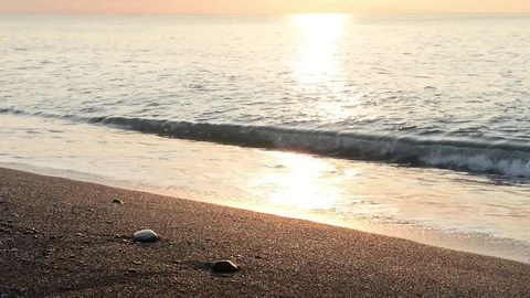 The sun rises on the beach while the waves break on the shoreline Stock Footage 83915478