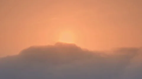 Sun rises from behind the clouds at dawn Stock Footage