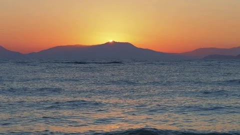 As the sun rises behind distant mountains, paints the sky in orange hues Stock Footage 315210978