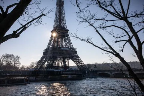 The sun rises behind the Eiffel Tower and Seine River in Paris Stock Photos