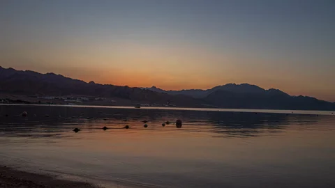 Sun rises from behind mountains and shines and beautiful lake, time lapse Stock Footage 259804208