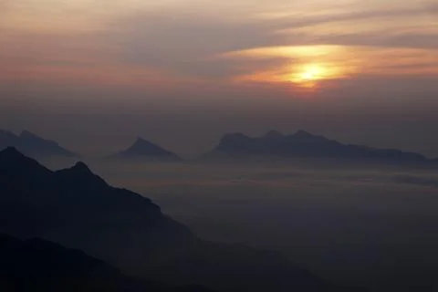 Sun rises between the misty mountains and clouds Stock Photos