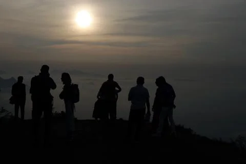 Sun rises between the misty mountains and clouds and group of people watching Foto stock