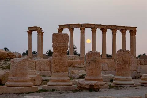 Sun rises between the stone pillars of the ancient ruins in Palmyra, Syria. Stock Photos