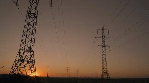 The Sun Rises from Beyond Horizon and Shines Through High Voltage Transmission Stock Footage 113515055