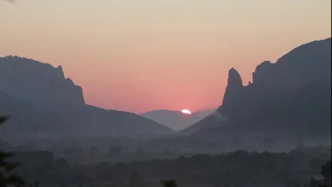 The sun rises from the horizon and rises into the sky passing behind the canyon. Video stock 70072464