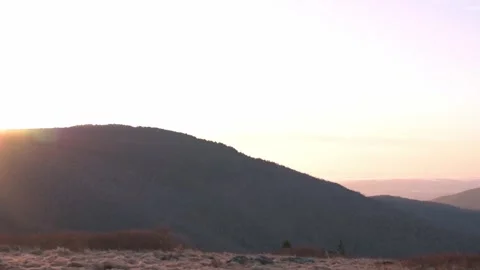 The sun rises over a mountain, casting a warm glow across the landscape. A Stock Footage 278073072