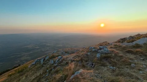 Sun rises over rugged hilltop, casting golden glow. Mount Rtanj sunrise Serbia Stock Footage 344686148