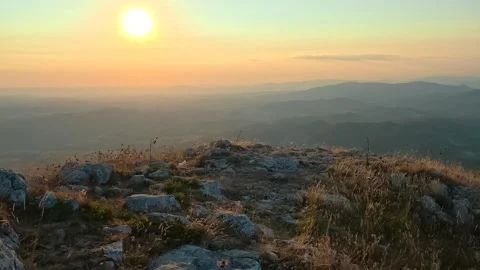 Sun rises over rugged hilltop, casting golden light. Mount Rtanj sunrise Serbia Stock Footage 344686561