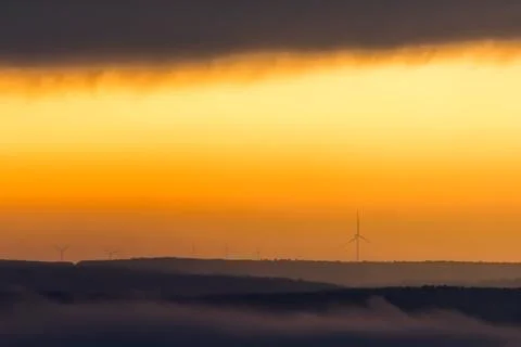 The sun rises over the wind power wheels Stock Photos