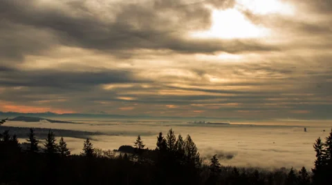 Sun rising behind clouds with fog covering city Stock Footage 35109593
