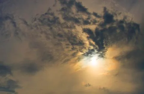 Sun rising behind the dark clouds, dark orange tone. Stock Photos
