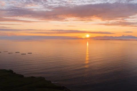 Sun rising behind low clouds at sea in Scotland Stock Photos