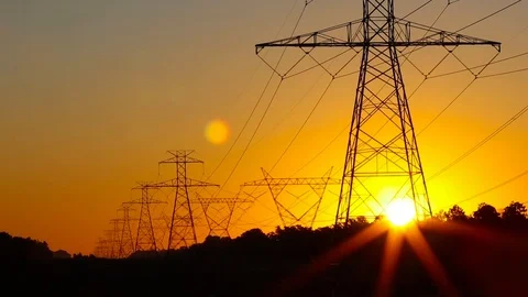 The sun rising behind a pair of towering electricity pylons. Stock-Footage 117807085