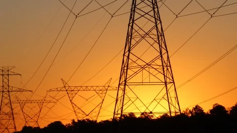 The sun rising behind a pair of towering electricity pylons. 4K Stock Footage 117807117