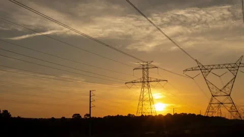 The sun rising behind a pair of towering electricity pylons Stock Footage 247837639