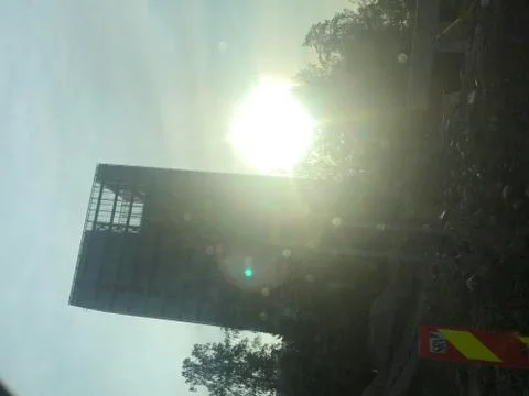 Sun rising behind a skyscraper Stock Photos