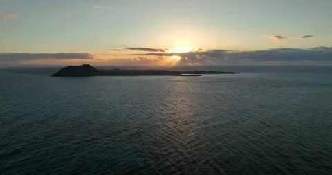 Sun rising behind small island in the sea Stock Footage 345422094