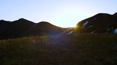 Sun rising from behind snow mountains. Tight shot with a beautiful lens flare Stock Footage 70703346