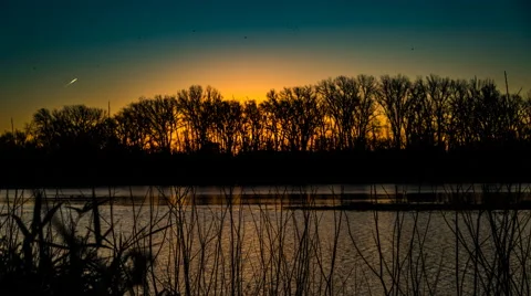 Sun Rising behind trees across river 8k Stock Footage 57459567