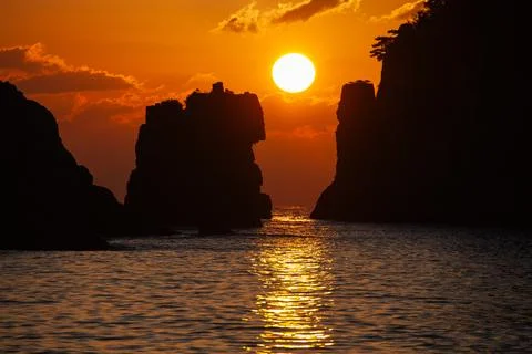 The sun rising between the lion-like rock and the rock. Stock Photos