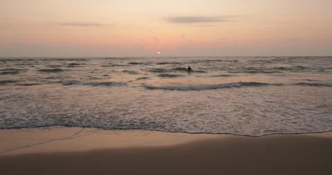 Sun rising as dim disk over ocean waves with pastel gradient sky Stock Footage 345645747