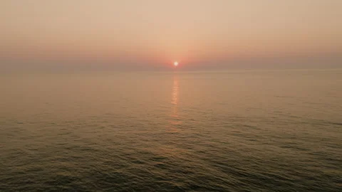 Sun rising over the ocean as drone rises up 库存影片 208899645