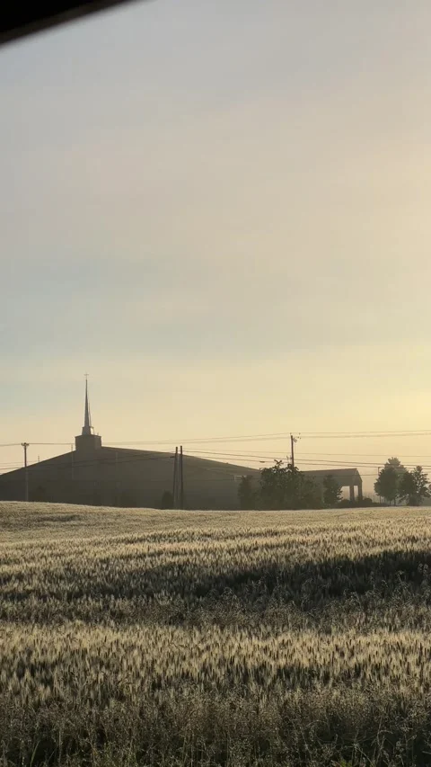 Sun rising over a wheat field and a church Stock Footage 196117743