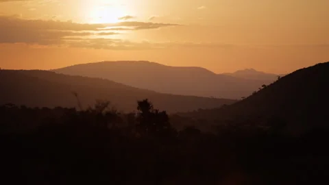 Sun rising in rolling hills in savannah with few clouds Stock Footage 310972956