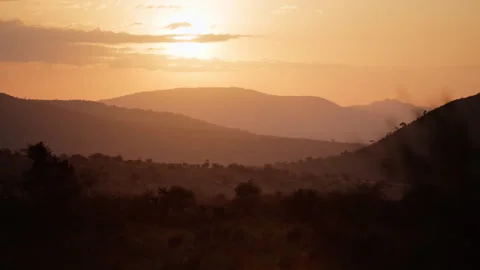 Sun rising in rolling hills in savannah with few clouds Stock Footage 310977786