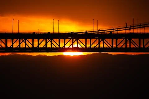 The sun rising through the clouds and cars passing through the bridge Stock Photos