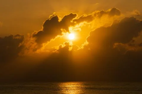 The Sun rising through clouds over the sea background Fotos Stock