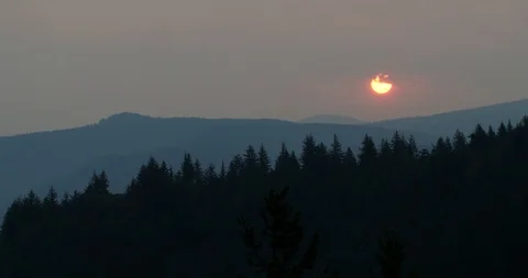 Sun rising through clouds in smoky sky in the Columbia River Gorge Stockbeeldmateriaal 104454740