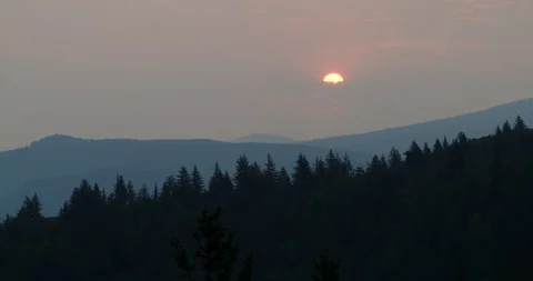 Sun rising through clouds in smoky sky in the Columbia River Gorge Stockbeeldmateriaal 104454842