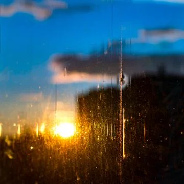 Sun Rolling Down Behind Black City Buildings through the Aged Window Glass Stock Photos