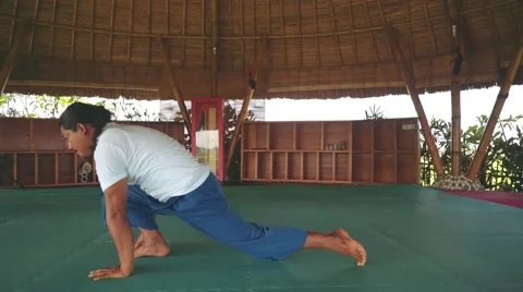 Sun salutation part with Standing Forward Bend pose by balinese man doing yoga Stock Footage 68084540