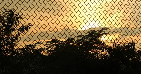 Sun set Shining Through Metal Wire Mesh Fence Stock Footage 290364932