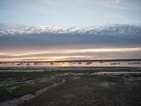 Sun set sky dramatic clouds sea front beach harbor marina boats moored landsc Foto stock