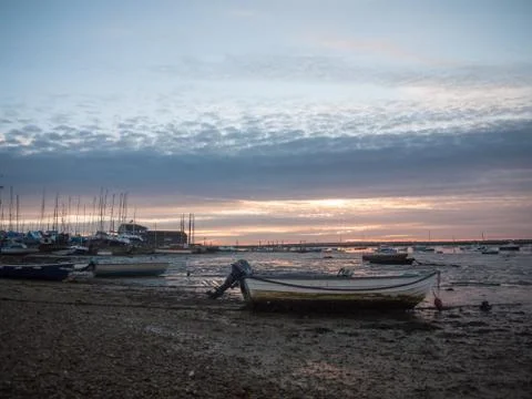 Sun set sky dramatic clouds sea front beach harbor marina boats moored landsc Stock Photos