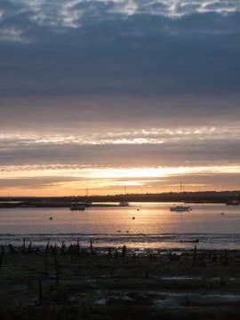 Sun set sky dramatic clouds sea front beach harbor marina boats moored landsc Stock Photos