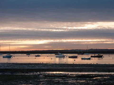 Sun set sky dramatic clouds sea front beach harbor marina boats moored landsc Stock Photos