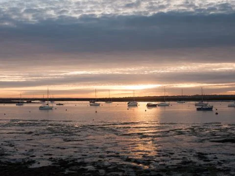 Sun set sky dramatic clouds sea front beach harbor marina boats moored landsc Stock Photos