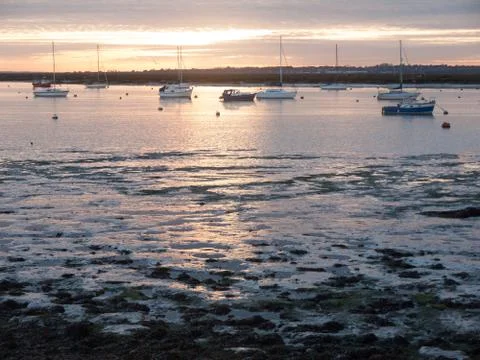 Sun set sky dramatic clouds sea front beach harbor marina boats moored landsc Stock Photos