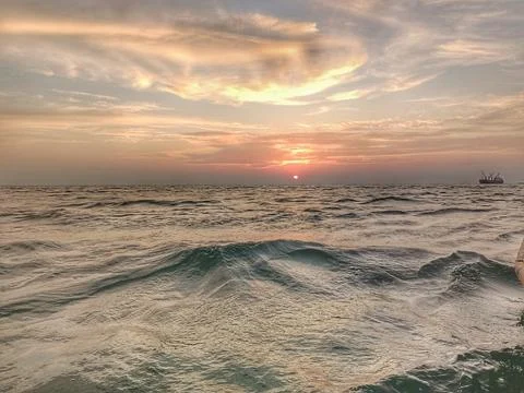 Sun sets and the waves crash on the ocean. Stock Photos