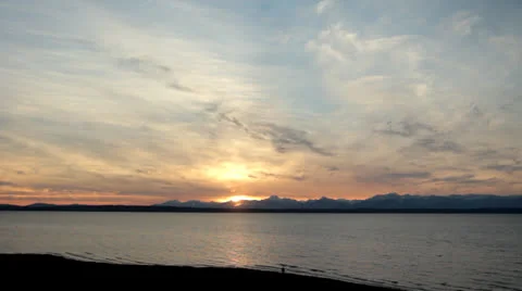 Sun Sets On Beach with Mountain Range Person watches Video stock 25139715