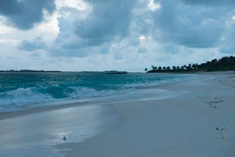Sun sets on beautiful blue waves in Caribbean sea crash to sandy beach C Stock Photos