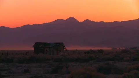 The sun sets behind an abandoned cabin the desert. Stock Footage 26926278